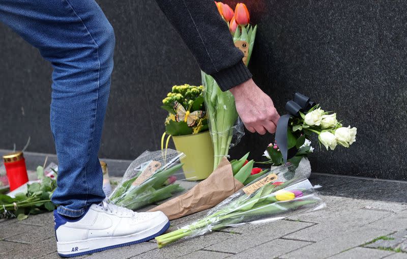 Man lays down flowers at one of the crime scenes following a shooting in Hanau