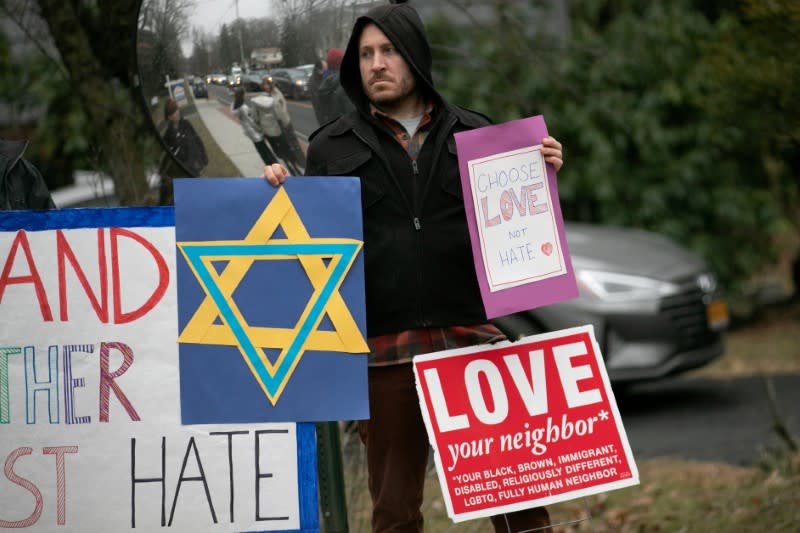 FILE PHOTO: A man holds a sign outside the home of rabbi Chaim Rottenberg in Monsey