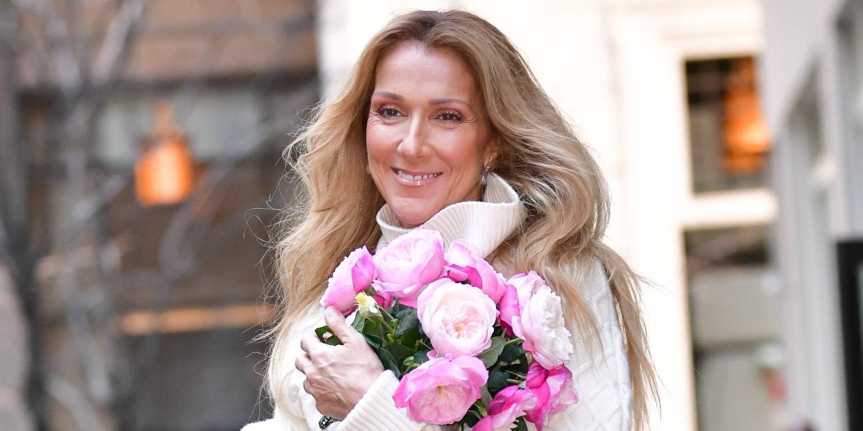 celine dion holding a bouquet of flowers and smiling while walking through new york city