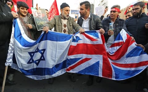 Iranian demonstrators prepare to burn a Union Jack and Israeli flag in front of the British embassy in Iran's capital Tehran on January 12