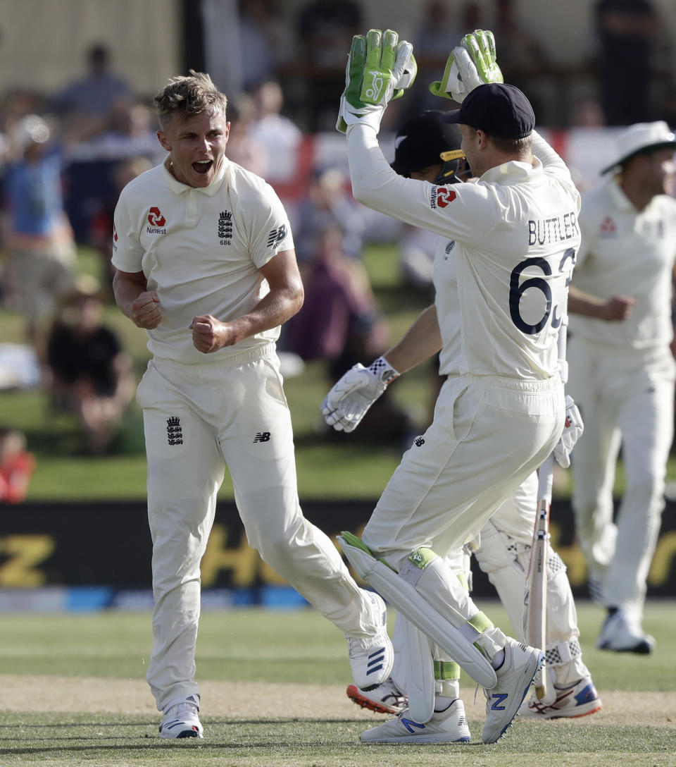 England's Sam Curran, left, celebrates with teammate Jos Buttler after dismissing New Zealand's Kane Williamson during play on day two of the first cricket test between England and New Zealand at Bay Oval in Mount Maunganui, New Zealand, Friday, Nov. 22, 2019. (AP Photo/Mark Baker)