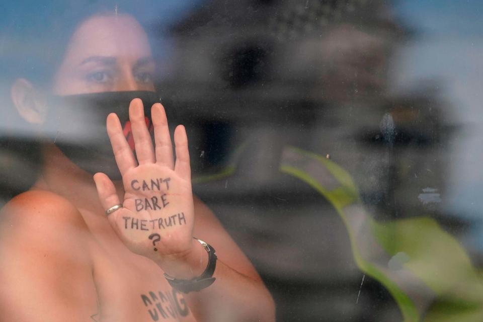 An activist from the Extinction Rebellion climate change group shows a message written on her hand as she is taken away in a police van after being arrested for locking herself to railings outside UK's parliament (AFP via Getty Images)