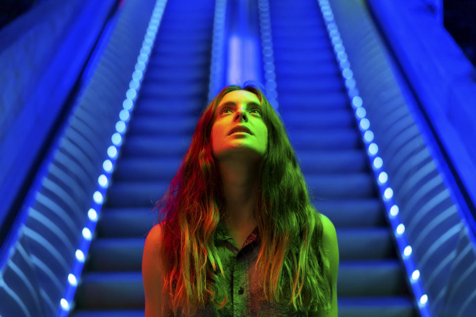 A woman looks up at a colorful image emitting green and red light