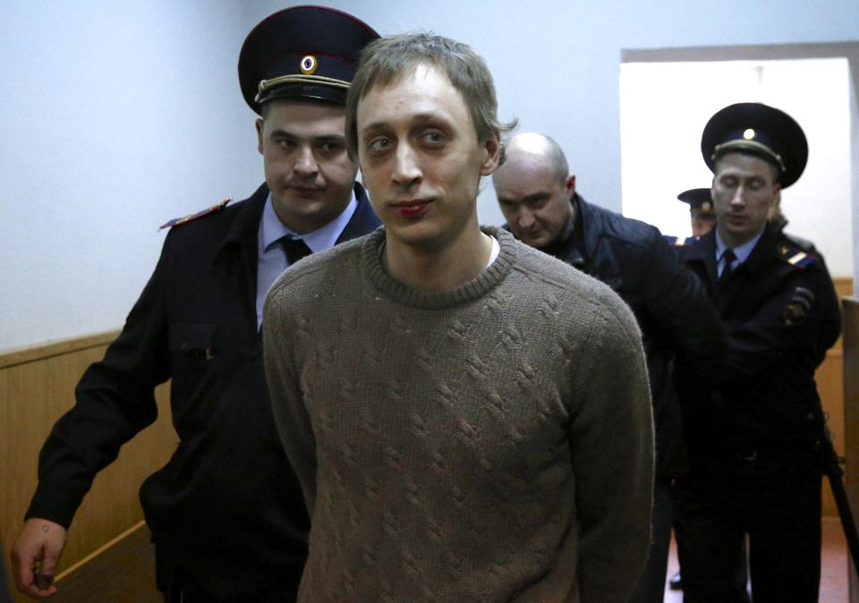 Pavel Dmitrichenko, center, is escorted to a court room in Moscow on Tuesday, Oct. 22, 2013. Bolshoi dancer Dmitrichenko goes on trial on Tuesday, on charges of organizing an acid attack against the ballet's artistic director, Sergei Filin. (AP Photo/Alexander Zemlianichenko)