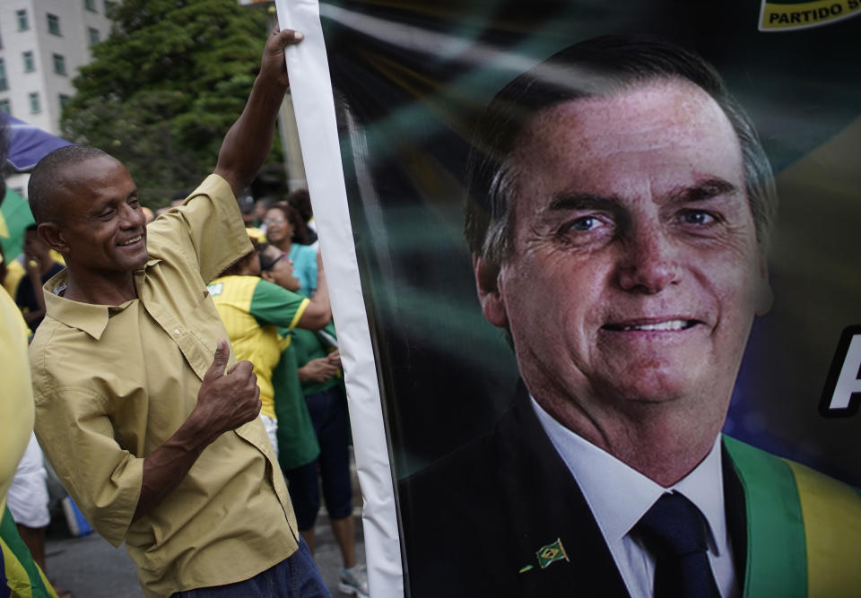 Un partidario del presidente brasileño Jair Bolsonaro ayuda a cargar una imagen gigante del mandatario durante una marcha en apoyo a él, en la playa de Copacabana en Río de Janeiro, Brasil, el domingo 26 de mayo de 2019. (AP Foto/Silvia Izquierdo)