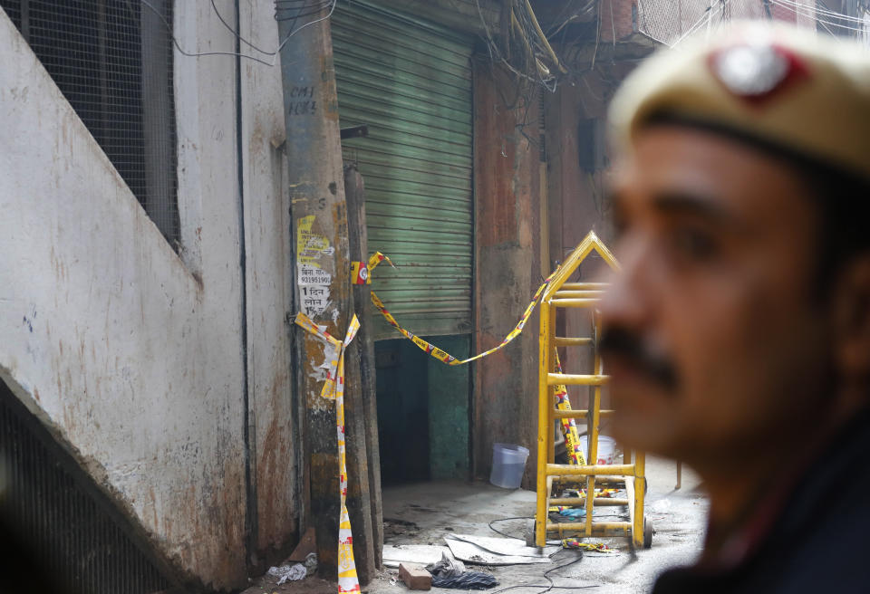 A policeman stands guard outside the only entrance of an ill-fated building which caught fire on Sunday, in New Delhi, India, Monday, Dec. 9, 2019. The victims of a devastating factory fire in central New Delhi early Sunday, in which dozens of people died, lived in a dense neighborhood packed with thousands of poor migrant workers from different Indian states forced to live and work in buildings without proper ventilation and prone to fire. (AP Photo/Manish Swarup)