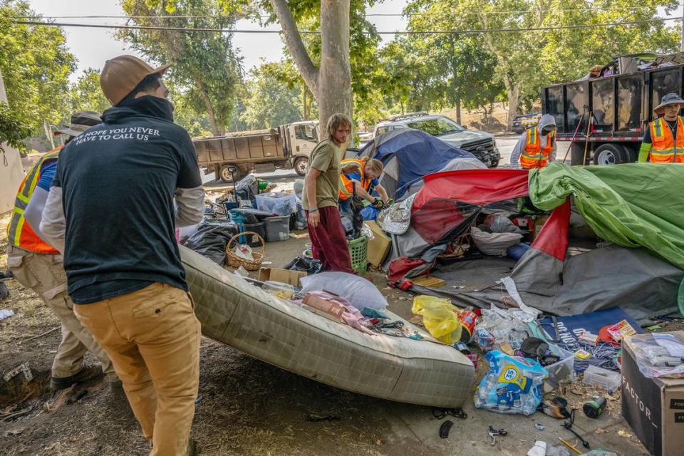 Tyler Vaneehei, 31, center, looks back as his mattress is readied to be thrown in the trash during a homeless sweep along C Street in Sacramento on Wednesday, July 19, 2023. He was able to save his tent but had no idea where he might go because he was afraid he had too many things to be accepted into the Miller Park Safe Ground. Officials were saying the homeless residents were only allowed three big bags and had to get rid of the rest of their belongings.