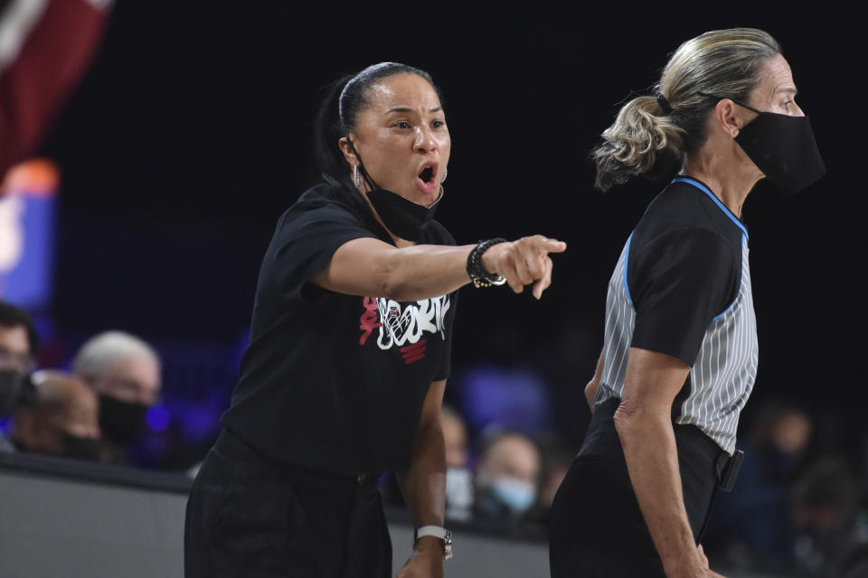 In this photo provided by Bahamas Visual Services, South Carolina head coach Dawn Staley gestures during an NCAA college basketball game against UConn at Paradise Island, Bahamas, Monday, Nov. 22, 2021. No. 1 South Carolina defeated No. 2 UConn 73-57. The official at right is unidentified. (Donald Knowles/Bahamas Visual Services via AP)