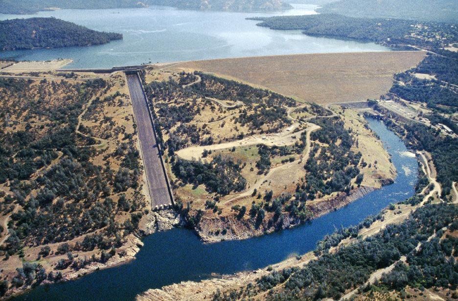 This June 23, 2005, aerial photo provided by the California Department of Water Resources shows Oroville Dam, Lake Oroville and the Feather River in the foothills of Sierra Nevada near Oroville, Calif. The concrete spillway that was undermined and developed huge holes in the last few days is at lower left. Release of water from the dam, the damaged spillway and the use of an earthen emergency spillway has caused a temporary evacuation on Sunday, Feb. 12, 2017, of thousands of people downstream. (Paul Hames/California Department of Water Resources via AP)