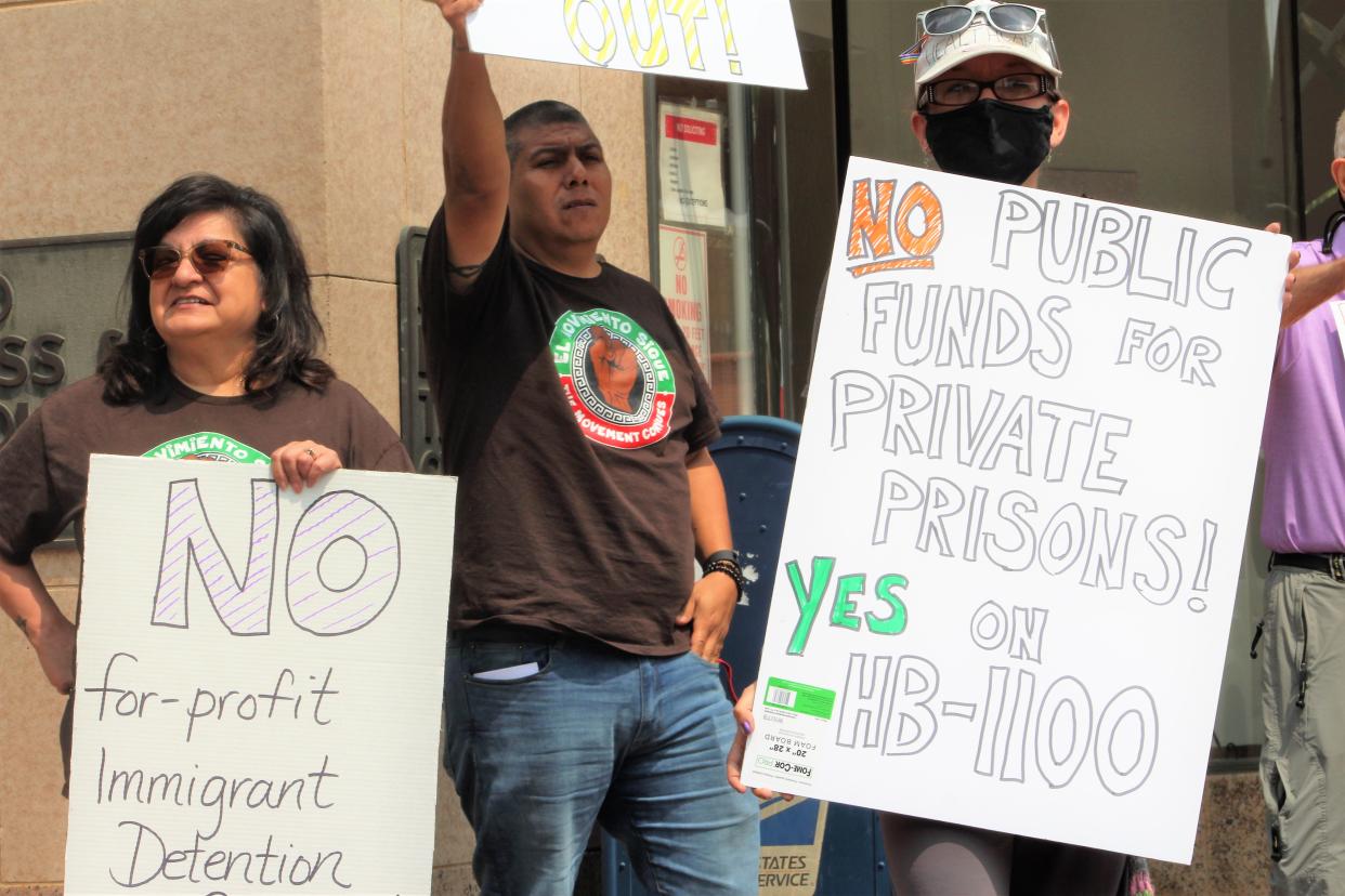 El Movimiento Sigue stakeholders and supporters including José Ortega (middle), and Kat Matthews (right), hold signs during a protest outside of the Pueblo Economic Development Corporation office on Tuesday. The group of around 20 were protesting a potential  governor's veto to a bill that would restrict state and local government participation in civil immigration detention.