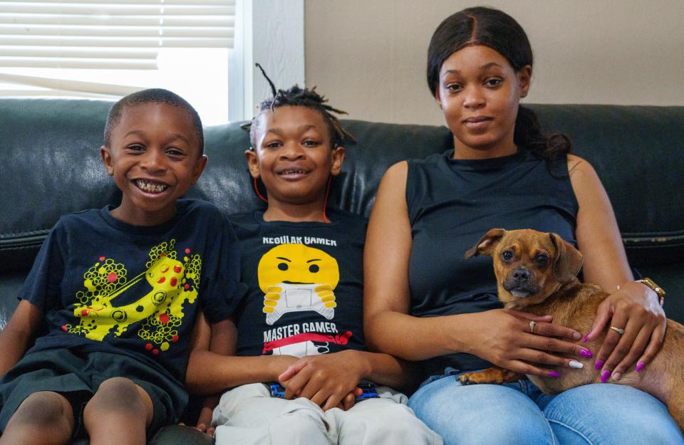 Ayanna White sits with sons Xavier, 11, and Elijah, 6, and dog, Max, on a couch inside their home Thursday, July 20, 2023, on Indianapolis' east side. Not pictured is White's oldest child, her daughter, Aaliyah, 12, who is visiting a family member. White says she has rented from Vinebrook Homes since July 2022, and has had numerous issues inside and outside her home.