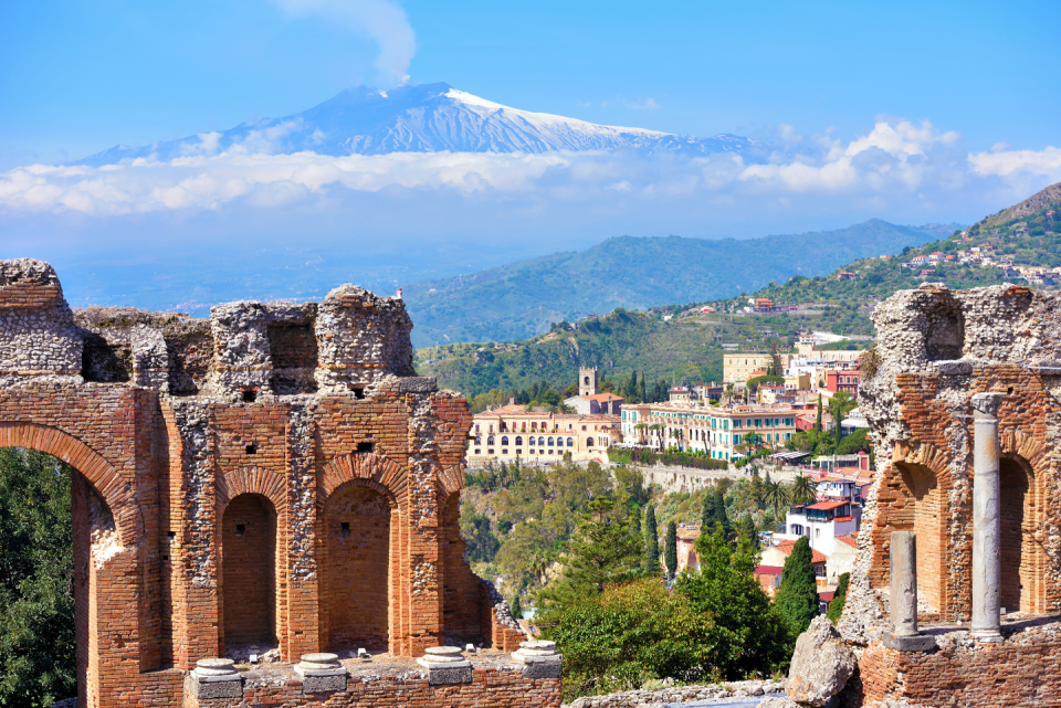 <p>A spectacular hilltop locale exuding medieval charm, Taormina is Sicily’s seductive summer hotspot. The Greek and Roman influences on its history make this city one of Italy’s most picturesque locations–one that’s attracted the likes of Oscar Wilde, Woody Allen, and even Elizabeth Taylor. </p><p>An underrated view often overlooked for other Italian hotspots is that of Teatro Antico, where the crystalline waters of the Ionian Sea and the distant smoking cone of Italy’s most active volcano, Mount Etna, create a jaw dropping take on Taormina. The theater is still in use, often hosting festivals, concerts, and plays, which makes this vantage point even more culturally immersive. After an afternoon exploring this impressive archeological location, wandering the streets of Taormina is just as captivating as seeing it from above.</p>