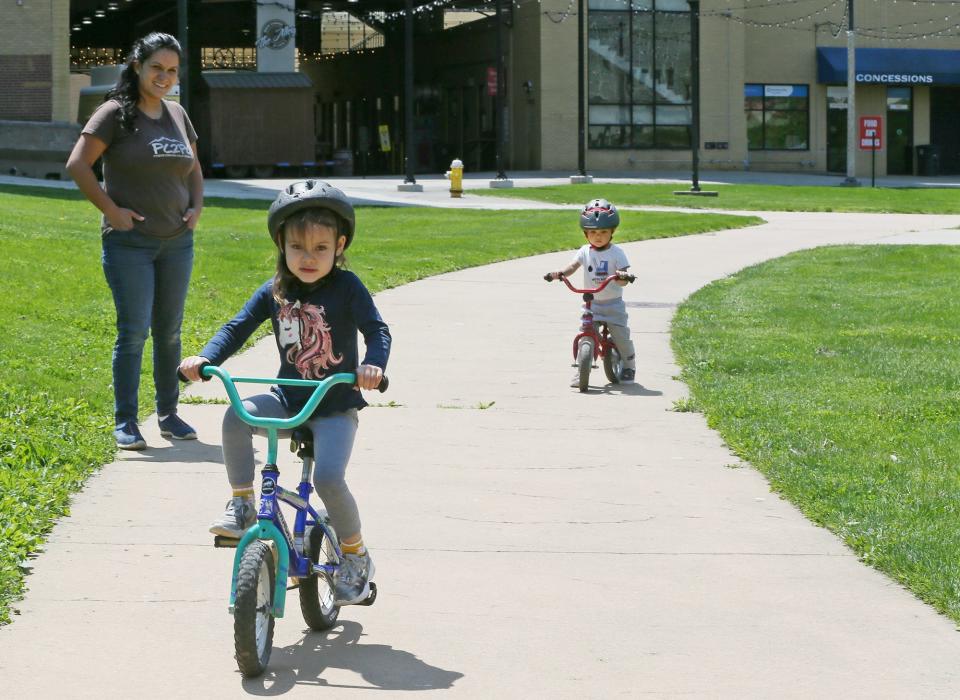 Angelina Newmyer watches her children, Aurora, 4, and Albert, 2, ride their bikes in Lock 3 in Akron on Tuesday.