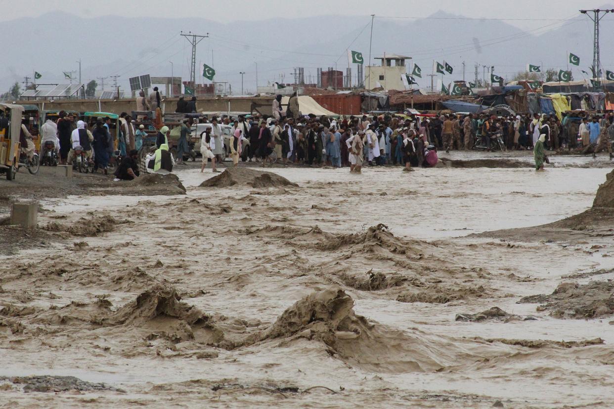 People wade through muddy floodwater in the town of Chaman in Balochistan province.