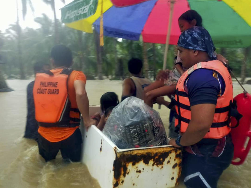 In this photo provided by the Philippine Coast Guard, rescuers use an old refrigerator as a float as they evacuate residents from flood waters caused by Tropical Storm Nalgae in Hilongos, Leyte province, Philippines on Friday Oct. 28, 2022. Flash floods and landslides set off by torrential rains left dozens of people dead, including in a hard-hit southern Philippine province, where many villagers are feared missing and buried in a deluge of rainwater, mud, rocks and trees, officials said Saturday. (Philippine Coast Guard via AP)