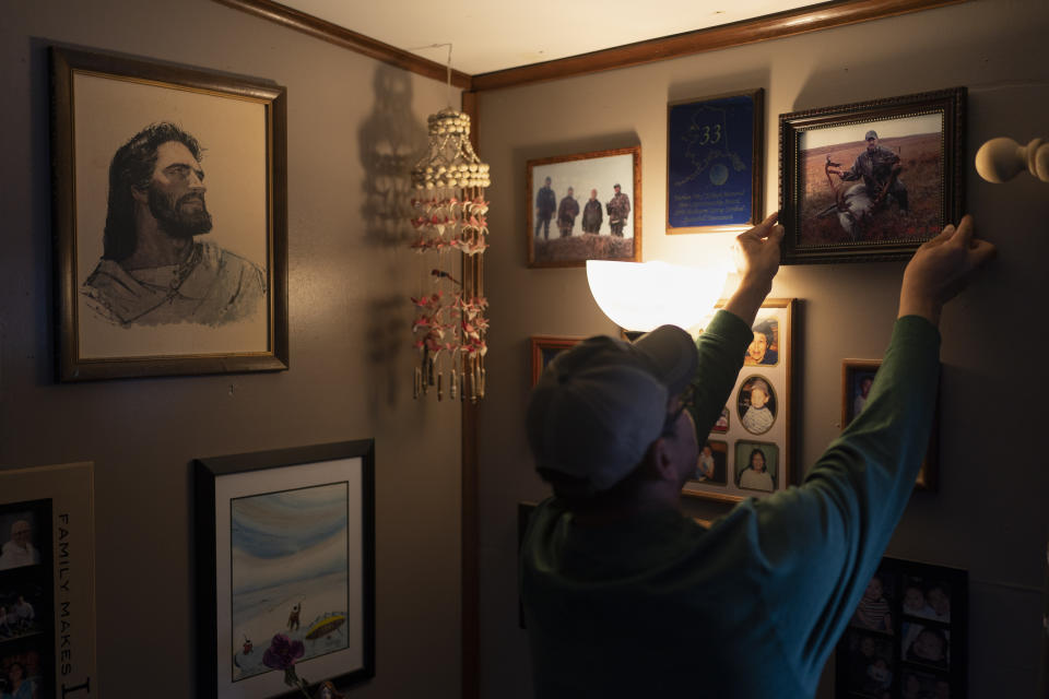 John Kokeok, 46, hangs a framed photo of his brother, Norman, back on the wall after an interview with The Associated Press in Shishmaref, Alaska, Monday, Oct. 3, 2022. Norman died in 2007 after his snowmobile fell through ice that melted earlier than usual. (AP Photo/Jae C. Hong)