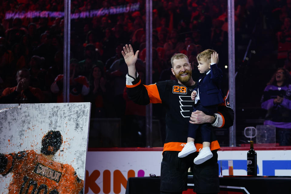 Philadelphia Flyers' Claude Giroux, left, and his son, Gavin wave during a ceremony honoring Giroux's 1000th game as a Flyer before an NHL hockey game against the Nashville Predators, Thursday, March 17, 2022, in Philadelphia. (AP Photo/Matt Slocum)