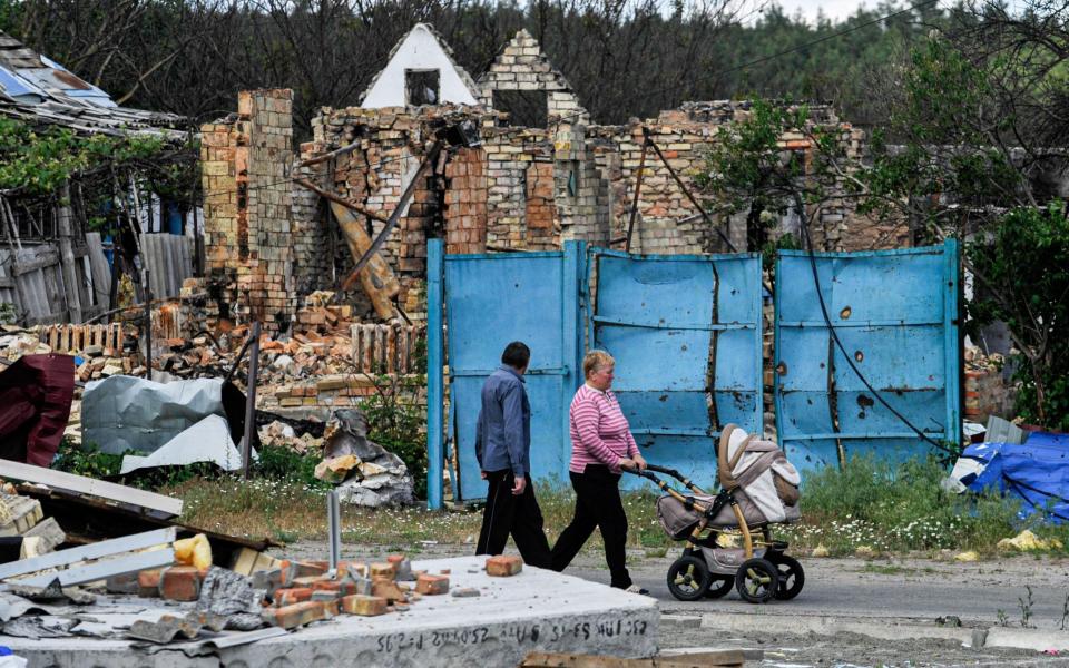 People walk past a house destroyed by Russian shelling at Mykhailivka-Rubezhivka village near the Ukrainian capital Kyiv - Sergei Chuzavkov/SOPA Images/Shutterstock /Shutterstock 