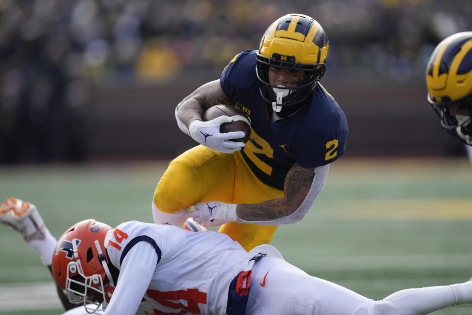 Michigan running back Blake Corum (2) runs the ball as Illinois defensive back Xavier Scott (14) defends in the first half of an NCAA college football game in Ann Arbor, Mich., Saturday, Nov. 19, 2022. (AP Photo/Paul Sancya)