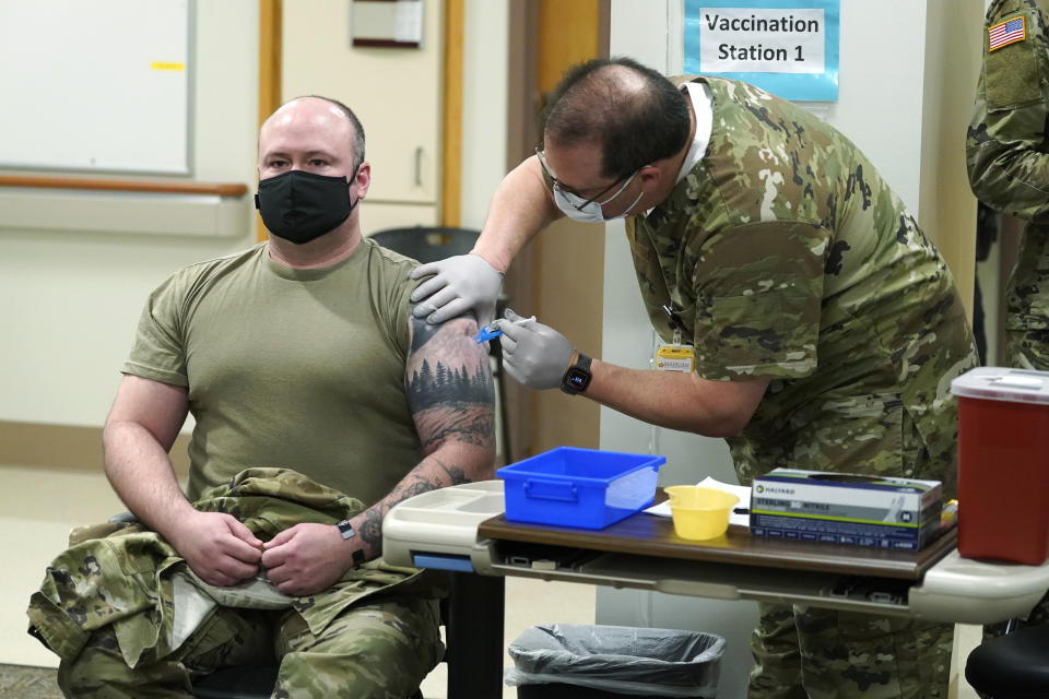 Maj. Jeffery Wittkopp, left, a Physician Assistant in the Emergency Department at Madigan Army Medical Center, receives one of the first doses of the Pfizer vaccine for COVID-19 from nurse Jose Picart, right, Wednesday, Dec. 16, 2020, at Joint Base Lewis-McChord in Washington state, south of Seattle. Vaccinations are scheduled to continue in the coming weeks for front-line medical workers and and others in high-priority positions at the base. (AP Photo/Ted S. Warren)