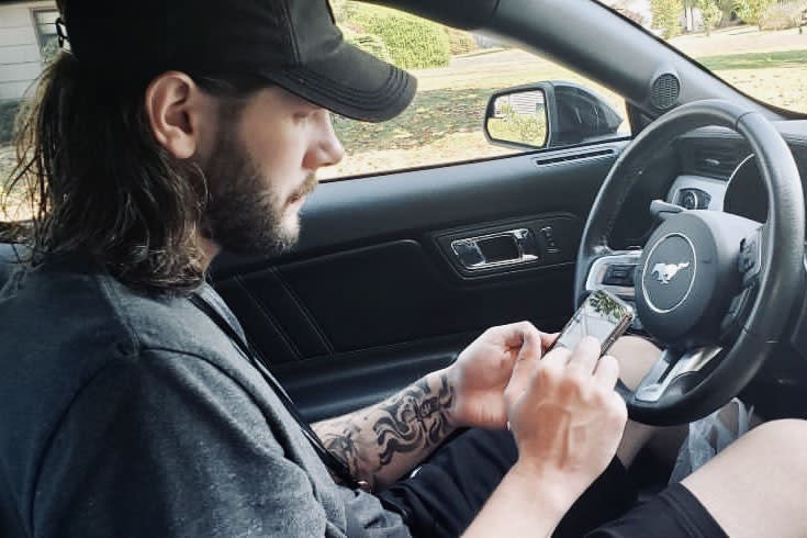 A man checks his phone in his car.