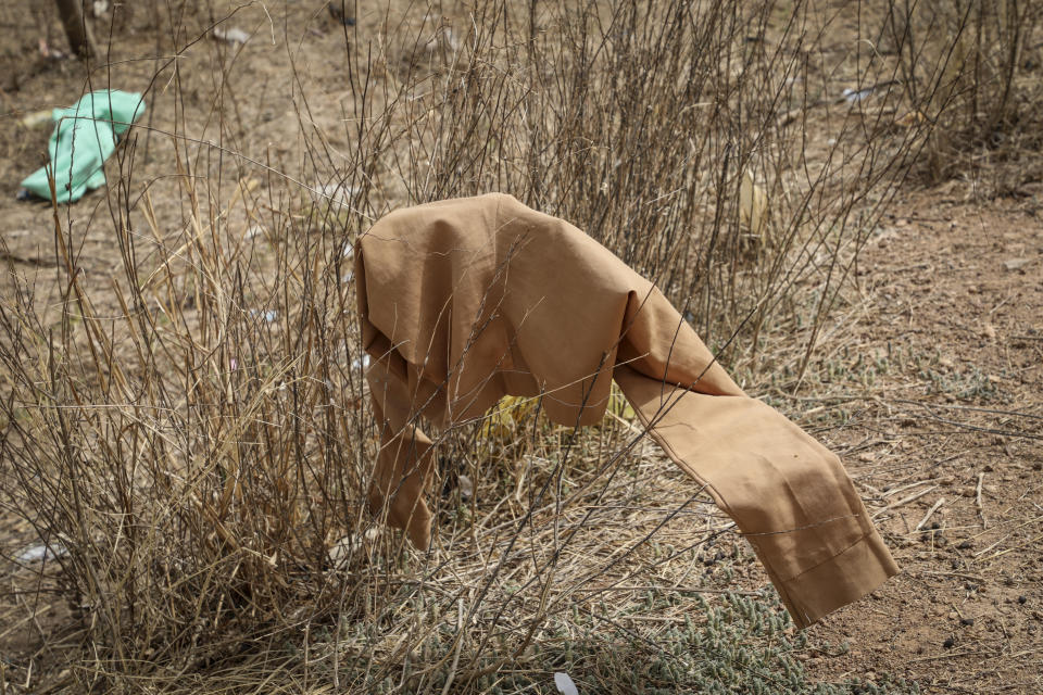 A piece of school clothing hangs on a bush outside the Government Girls Junior Secondary School from where more than 300 girls were abducted on Friday by gunmen, in Jangebe town, Zamfara state, northern Nigeria Saturday, Feb. 27, 2021. Nigerian police and the military have begun joint operations to rescue the more than 300 girls who were kidnapped from the boarding school, according to a police spokesman. (AP Photo/Ibrahim Mansur)