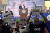 <p>Gegner von US-Präsident Donald Trump halten während seiner Rede bei einer Gewerkschaftsversammlung in Washington Schilder mit der Aufforderung „Resist“ („Widerstand leisten“) hoch. (Bild: AP Photo/Susan Walsh) </p>