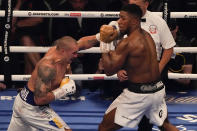 Oleksandr Usyk of Ukraine, left, throws a punch at Anthony Joshua of Britain during their WBA (Super), WBO and IBF boxing title bout at the Tottenham Hotspur Stadium in London, Saturday, Sept. 25, 2021. (AP Photo/Frank Augstein)