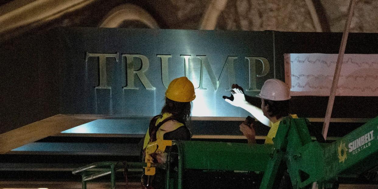 Workers remove the signage for the Trump International Hotel, in the dark and illuminated by a flashlight, Wednesday, May 11, 2022, in Washington.