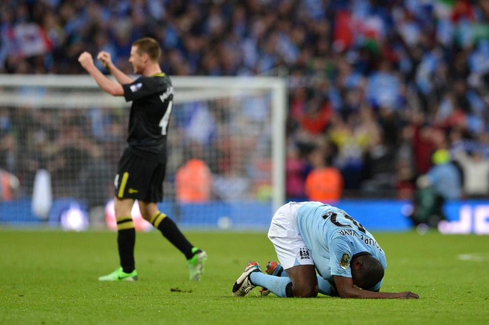 Manchester City's Yaya Toure (right) is left dejected on the floor as Wigan Athletic's James McCarthy celebrates their victory, after the final whistle