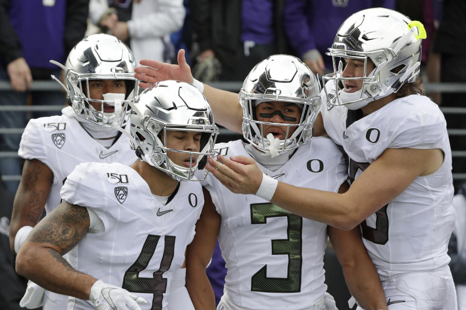 Oregon quarterback Justin Herbert, right, reaches over Johnny Johnson III (3) to congratulate Mycah Pittman (4) on Pittman's 36-yard touchdown reception against Washington in the second half of an NCAA college football game Saturday, Oct. 19, 2019, in Seattle. Oregon won 35-31. (AP Photo/Elaine Thompson)