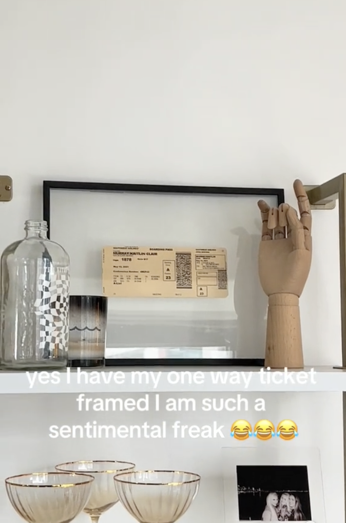 A shelf with a framed ticket, a wooden hand sculpture, glasses, and a bottle. Text overlay shares a personal message about sentimentality