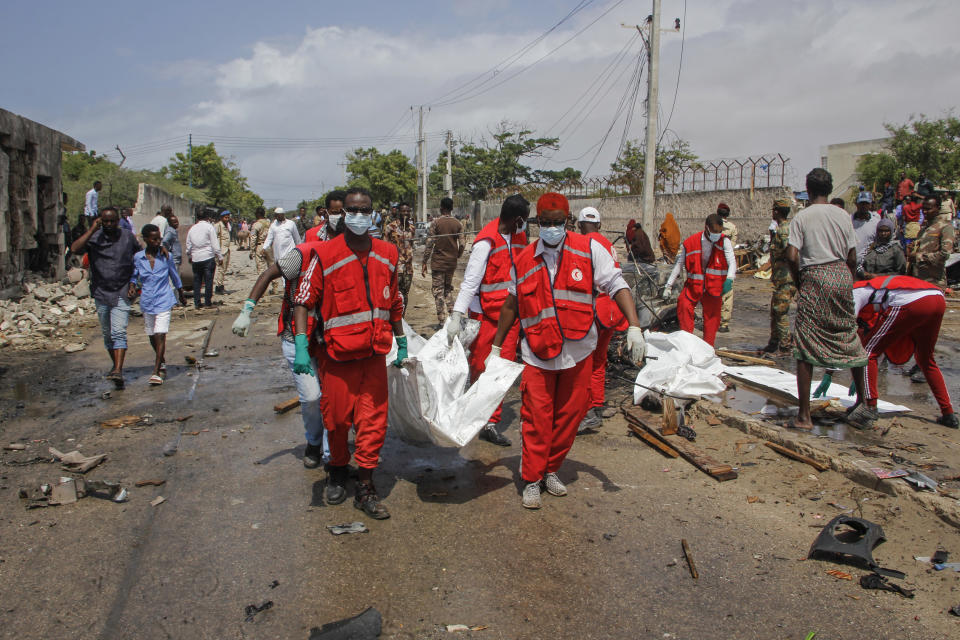 Medical workers carry the body of a civilian who was killed in a suicide car bomb attack that targeted the city's police commissioner in Mogadishu, Somalia Saturday, July 10, 2021. At least nine people are dead and others wounded after the large explosion, a health official at the Medina hospital said, noting that the toll reflected only the dead and wounded brought there. (AP Photo/Farah Abdi Warsameh)