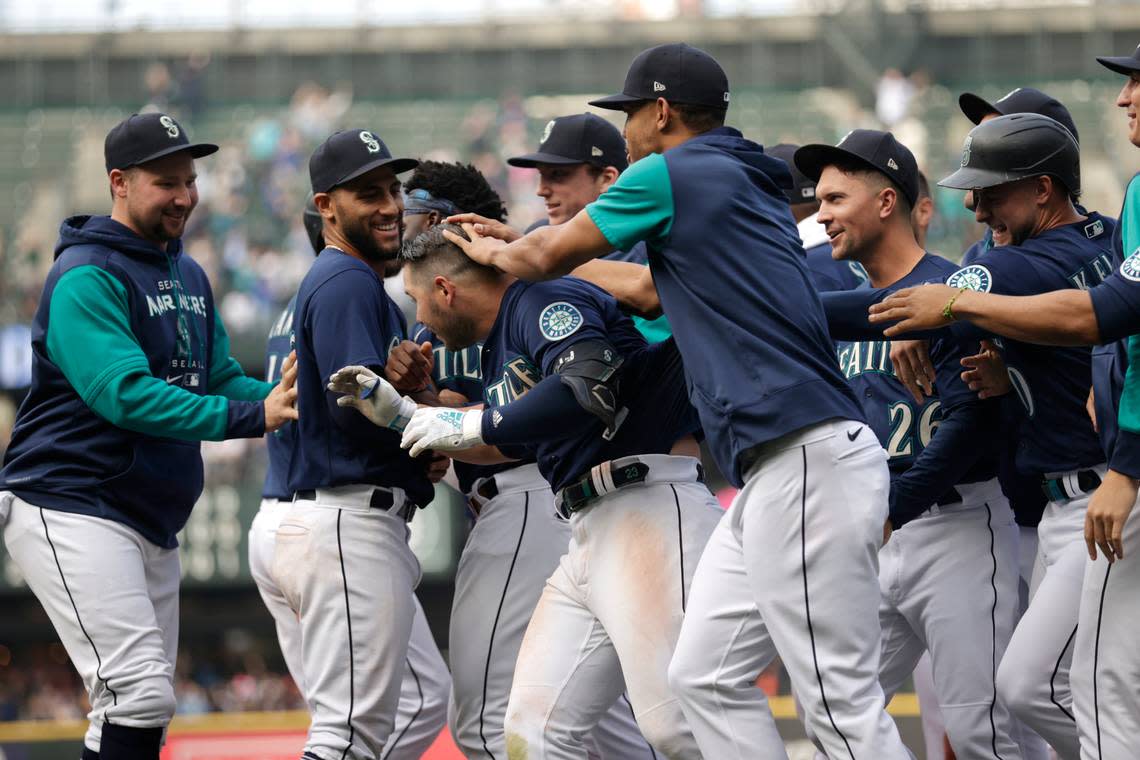 Seattle Mariners players surround and rub the head of Ty France after he drove in the winning run of the 5-4 over the Detroit Tigers during the ninth inning a baseball game, Wednesday, Oct. 5, 2022, in Seattle. (AP Photo/John Froschauer)