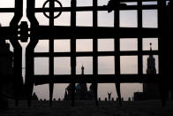 A man gestures in almost empty Red Square with St. Basil's Cathedral, center, and the Spasskaya Tower, right, seen through a part of a lattice of the Nikolsky Gate in Moscow, Russia, Sunday, March 29, 2020. The new coronavirus causes mild or moderate symptoms for most people, but for some, especially older adults and people with existing health problems, it can cause more severe illness or death. (AP Photo/Victor Berezkin)
