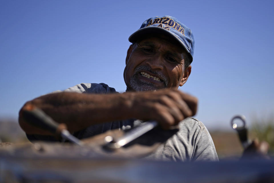 Jose Garcia works to remove a broken blade on a plow on a farm irrigated with water from the Colorado River, Sunday, Aug. 14, 2022, near Los Algodones, Mexico. (AP Photo/Gregory Bull)