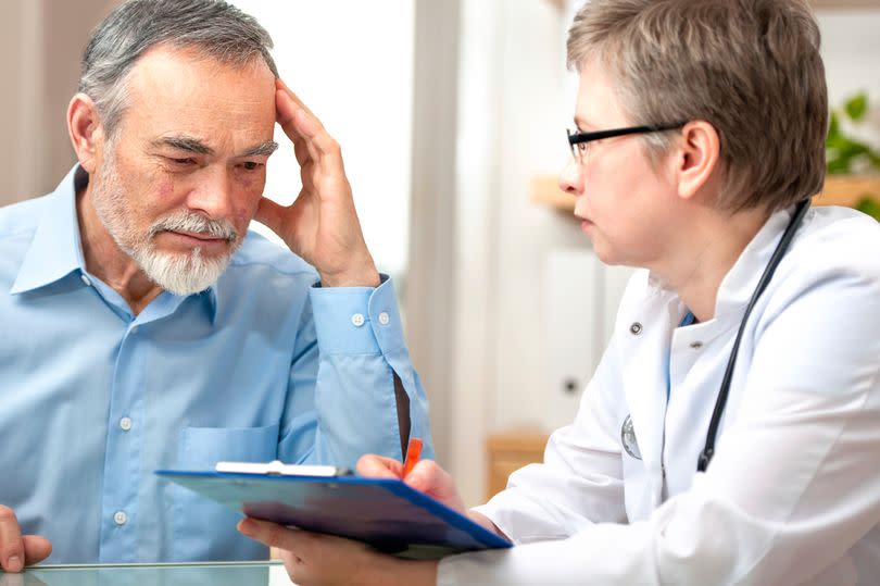 A puzzled man being spoken to by a doctor with a clipboard