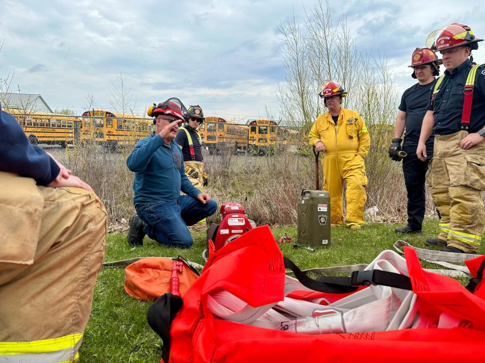 Instructor Colin Braney teaches a group of fire fighters how to pump water from a natural source. 