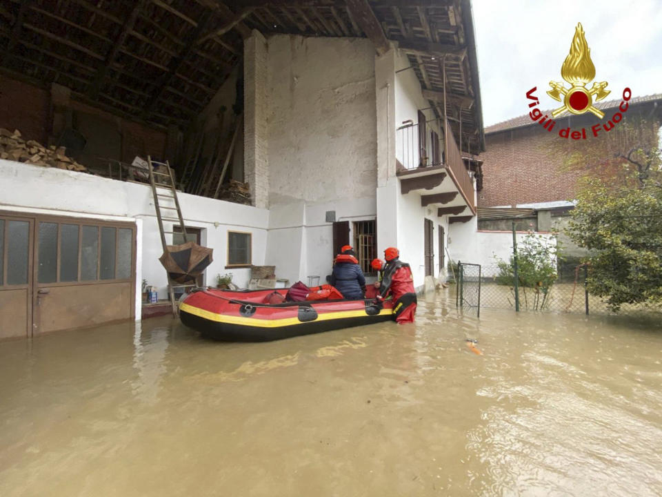 Firefighters on a dinghy evacuate people from house in Carde', near Cuneo, in the Piedmont region of northern Italy, after floods, Sunday, Nov. 24, 2019. Heavy rains and bad weather have been hitting most of Italy, causing river areas to overflood and isolate hamlets. (Italian Firefighters Vigili del Fuoco via AP)