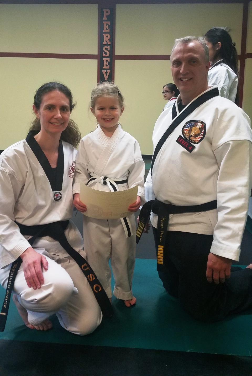 Malia posing with her daughter Noelle and Noelle's Taekwondo instructor, Scott Baker, on the day Noelle tested for a Tiger Cub black belt.