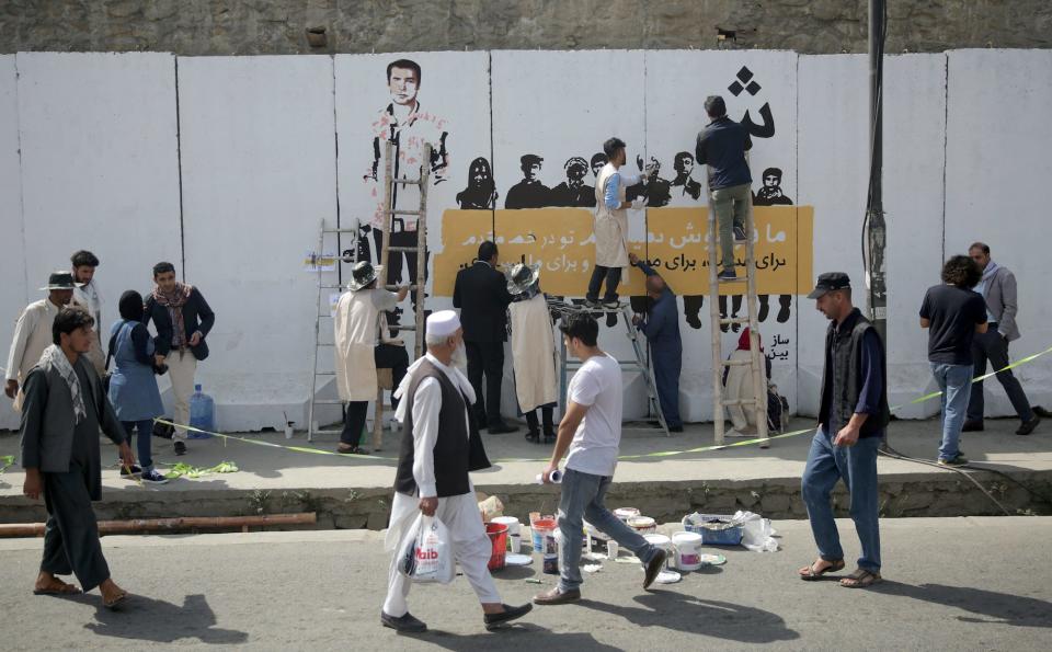 Artists paint a mural of killed journalists on a wall