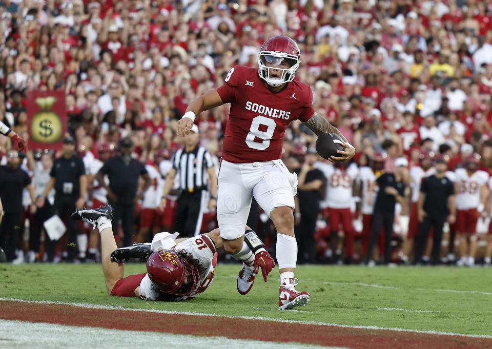 Oklahoma quarterback Dillon Gabriel (8) escapes a tackle by Iowa State defensive back Darien Porter (10) for a touchdown during the first half of an NCAA college football game Saturday, Sept. 30, 2023, in Norman, Okla. (AP Photo/Alonzo Adams)