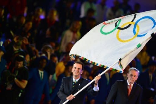 El alcalde de Rio de Janeiro, Eduardo Paes, ondea la bandera olímpica, este domingo en Londres. Rio de Janeiro tomó el domingo la posta olímpica en el cierre de los Juegos de Londres-2012 con un espectáculo que rindió homenaje al carnaval carioca, pero también mostró fusión musical y modernidad y tuvo como gran invitado sorpresa a "O Rei" Pelé. (AFP | gabriel bouys)