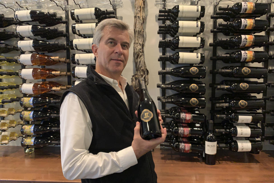 In this Oct. 4, 2019 photo, Michael Parr, vice president of international sales at Wente Vineyards, holds bottle of wine in a tasting room in Livermore, Calif. Caught in the crossfire of President Donald Trump’s trade war with China, U.S. vineyards are struggling to sell Syrah in Shanghai and Chardonnay in Shenzhen. They risk losing their foothold in one of the world’s fastest-growing wine markets. Among the casualties is California's Wente Vineyards, a family-run wine business that was among the first U.S. winemakers to export to China 25 years ago. (AP Photo/Terry Chea)