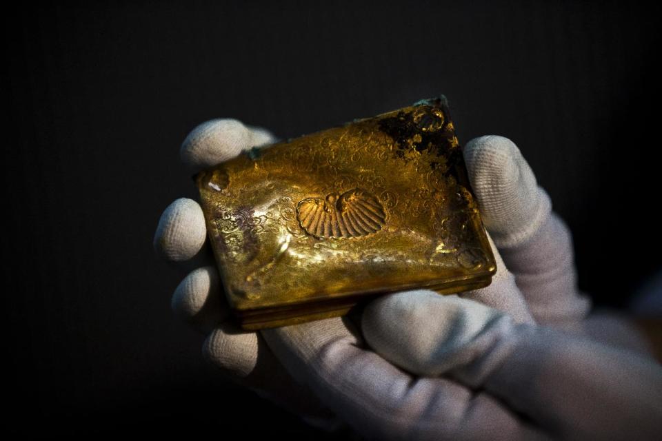 A worker of the ministry holds up for photographers a gold tobacco box from the shipwreck of a 1804 galleon, on its first display to the media at a Ministry building, in Madrid, Friday, Nov. 30, 2012. Spanish cultural officials have allowed the first peep at 16 tons (14.5 metric tons) of the shipwreck, 'Nuestra Senora de las Mercedes' a treasure worth an estimated $500 million that a U.S. salvage company gave up after a five-year international ownership dispute. (AP Photo/Daniel Ochoa de Olza)