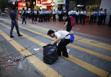 Pro-democracy protesters clean a street after policemen removed some barricades, at a protest site at the commercial area of Causeway Bay in Hong Kong October 14, 2014. REUTERS/Carlos Barria