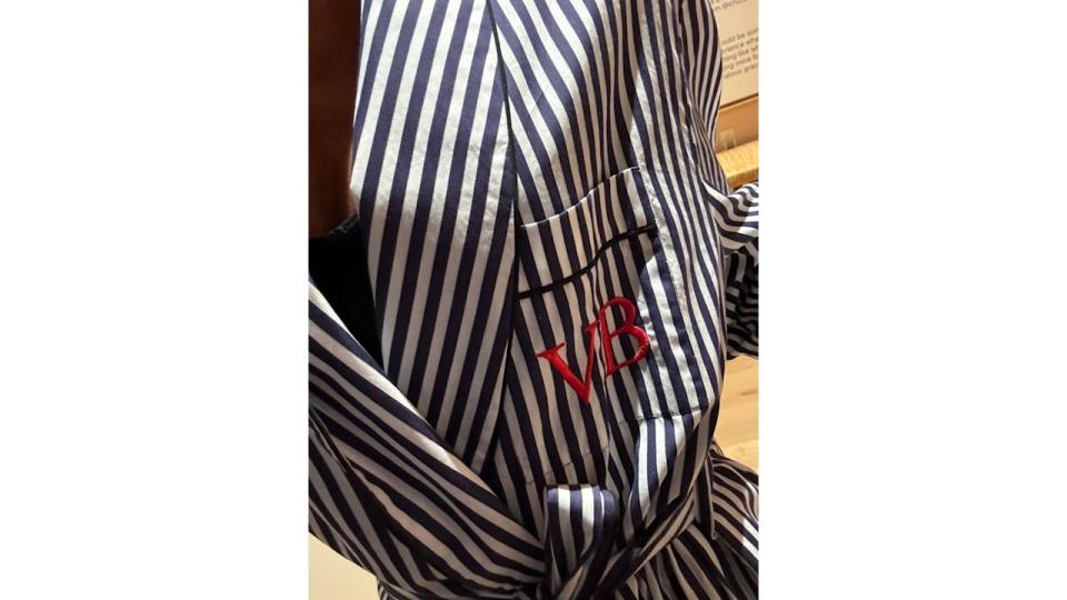 Victoria Beckham wears a striped dressing gown with her initials embroidered in red thread