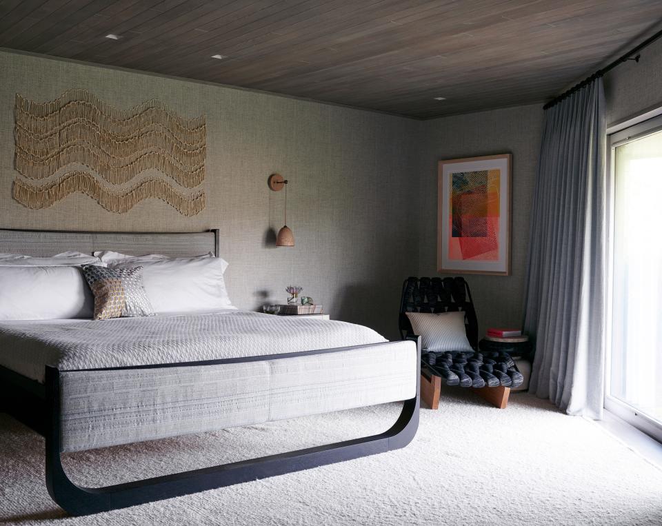 In this unevenly shaped guest bedroom, Patricia Urquiola’s Biknit chaise fits nicely into a windowside nook and harmonizes with the shapely look of the wood-framed bed from Skram. Above the bed is a wall sculpture by Lea Nordstrom made of hand-built porcelain bits, from Cocobolo Gallery.