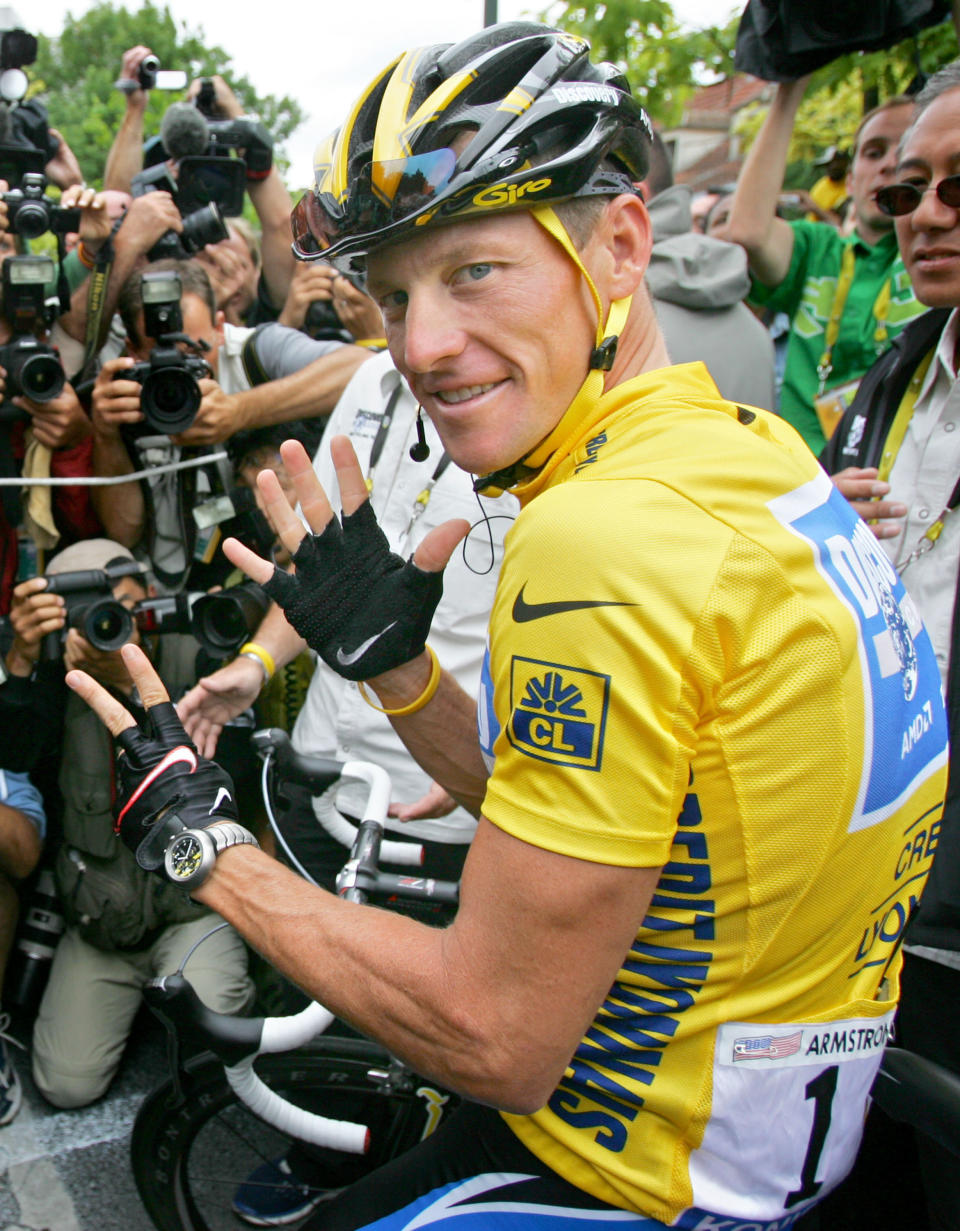 This is a July 24, 2005, file photo showing overall leader Lance Armstrong, of Austin, Texas, surrounded by press photographers, signaling seven, for his seventh straight win in the Tour de France cycling race, prior to the start of the 21st and final stage of the race, between Corbeil-Essonnes, south of Paris, and the French capital. 