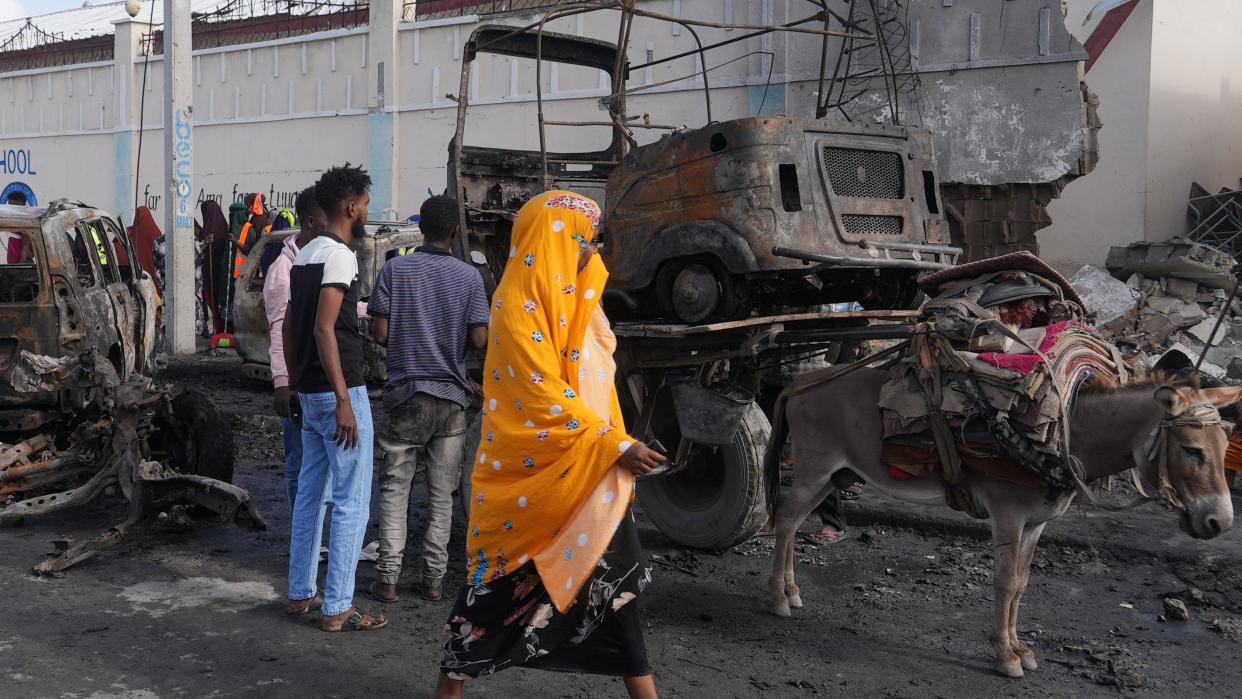 A woman walks past the scene of the attack, with burnt-out cars behind her